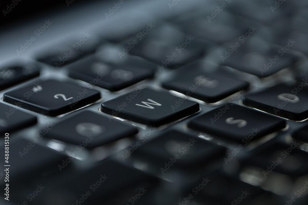 Modern backlit laptop keyboard with button W, close-up. Concept programming Modern backlit laptop keyboard with button W, close-up. Concept programming