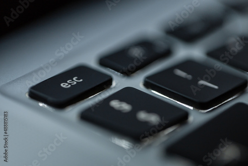 Modern computer keyboard with backlit and focus on the esc button, macro photo