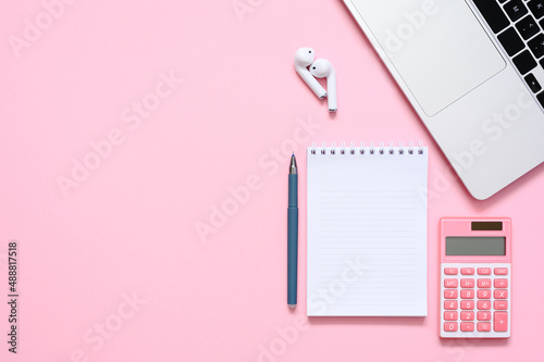Notepad, calculator and laptop on a pink background. View from above. The concept of planning expenses or income.