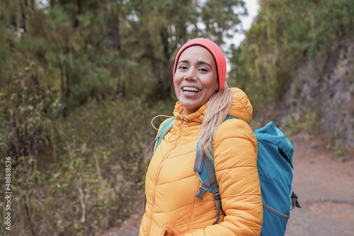 Young latin woman smiling on camera during trekking day at forest mountain