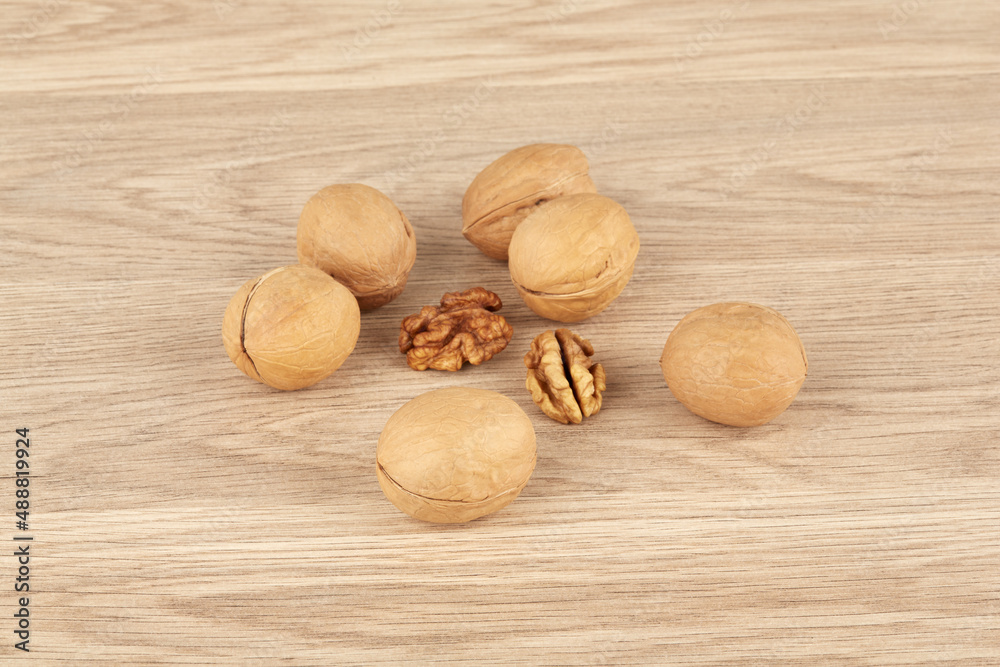 Whole walnuts on a wooden background together with peeled walnuts