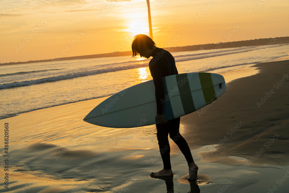 朝の海でサーフィンをする男性