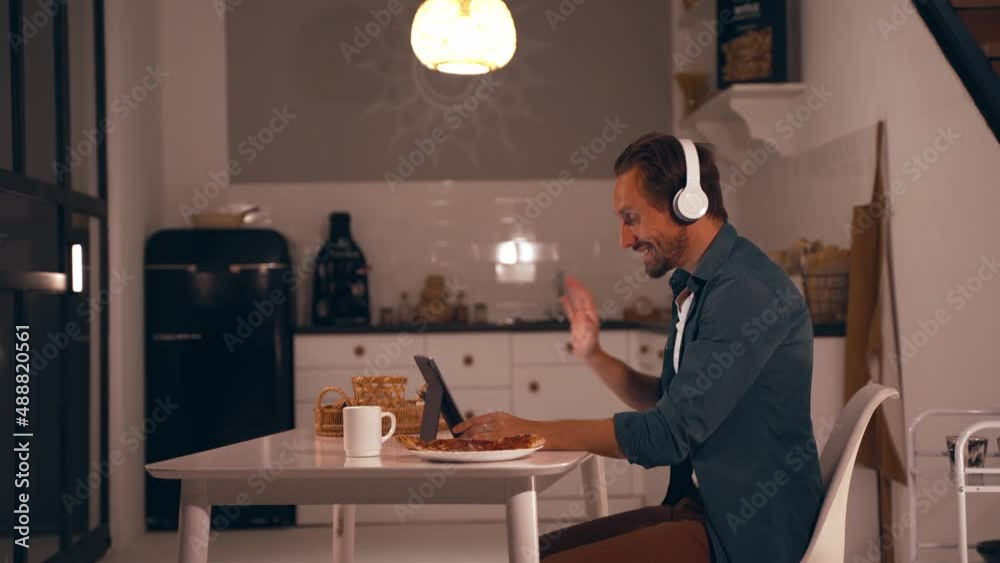 Male freelancer has video call with a client, looking at a tablet screen and discussing a new startup project while working from his home office. Male freelancer has video call with a client, looking at a tablet screen and discussing a new startup project while working from his home office.