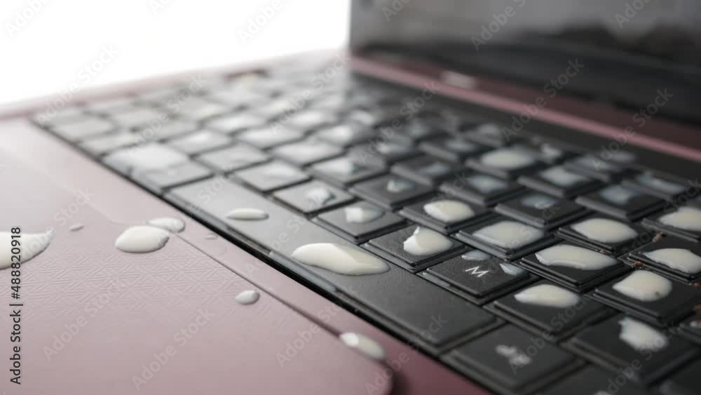 tea spilling over a laptop keyboard on table tea spilling over a laptop keyboard on table