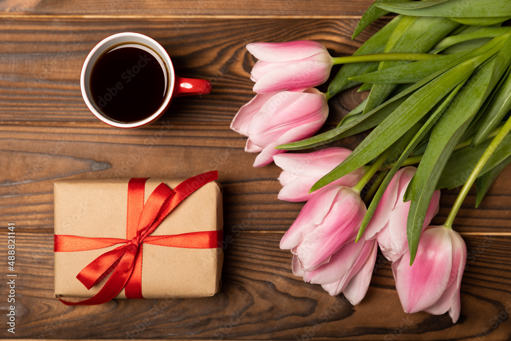International Women's Day. Beautiful postcard for March 8. Bouquet of pink tulips with a gift and fragrant coffee on a brown textured wood. Holiday concept. Copy space. Side view. International Women's Day. Beautiful postcard for March 8. Bouquet of pink tulips with a gift and fragrant coffee on a brown textured wood. Holiday concept. Copy space. Side view.