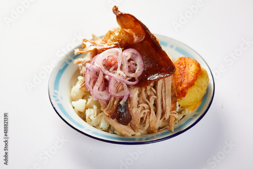 Hornado, a typical Ecuadorian dish that consists on pork cooked on firewood. It’s accompanied by llapingacho and mote. Served on a small plate on a white background.  photo