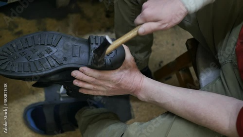 top view shoemaker knocks with a hammer on the sole of the shoe, slow motion. Repairing used shoes prolongs life and saves money photo