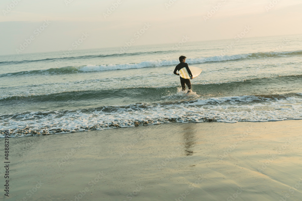 朝の海でサーフィンをする男性