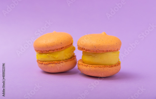 Delicious berry macaroons on a lilac paper background. French meringue cookies macaron. Culinary and cooking concept. Copy space.