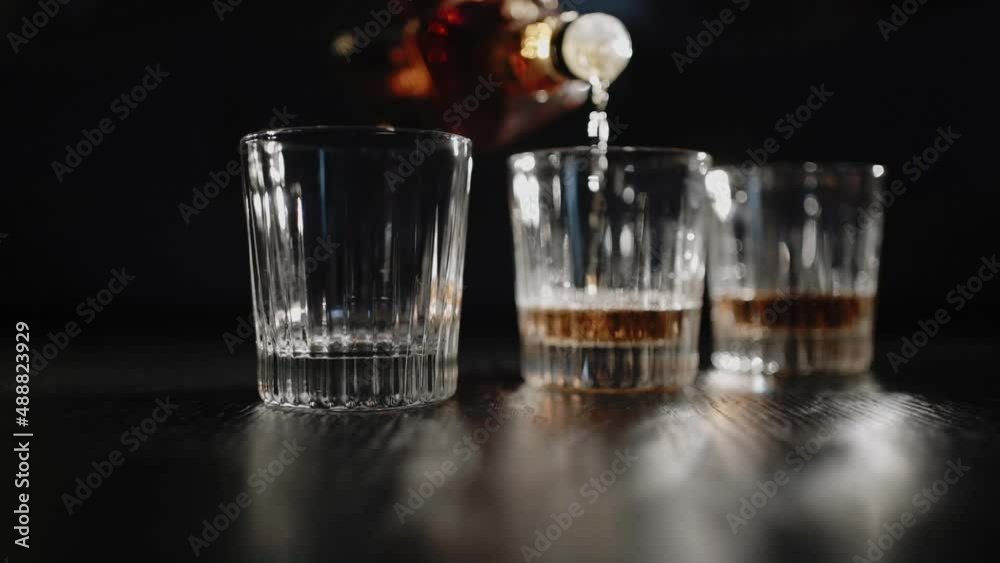 Soft focus video. Bartender pours alcohol drink in whisky glasses. Night party, holidays event. Barman working in restaurant. People drinking. Soft focus video. Bartender pours alcohol drink in whisky glasses. Night party, holidays event. Barman working in restaurant. People drinking.