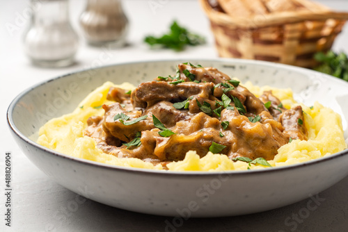 Traditional Russian dish Beef stroganoff with mashed potatoes in plate on concrete background
