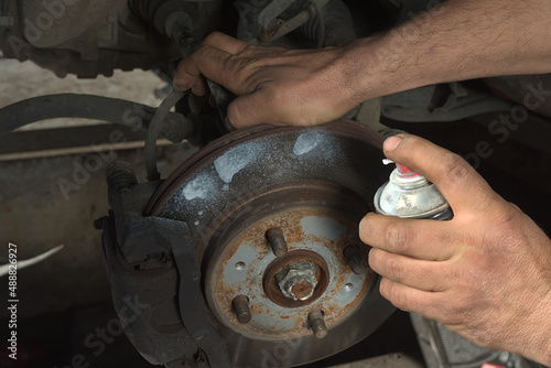Brake disc treatment with a lubricant cleaning spray to check the brake system of a car
