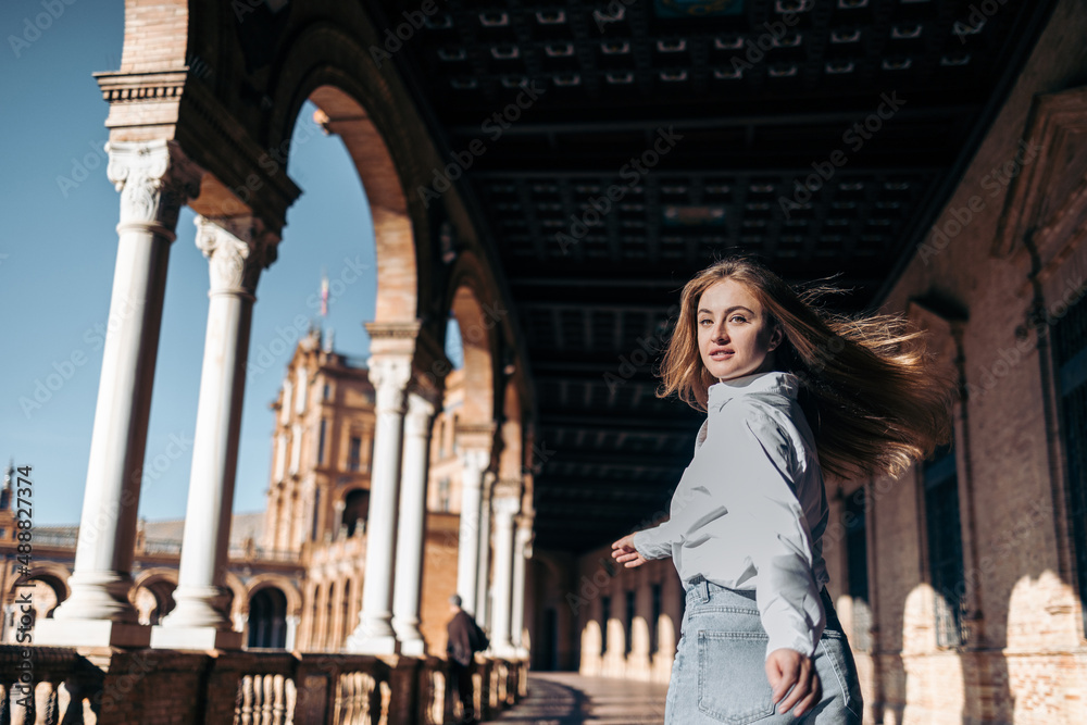 Young smiling Caucasian woman turning back sightseeing in Europe