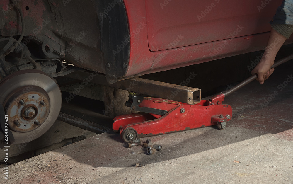 The hydraulic jack raises the car the wheel is removed from the brake disc The hydraulic jack raises the car the wheel is removed from the brake disc