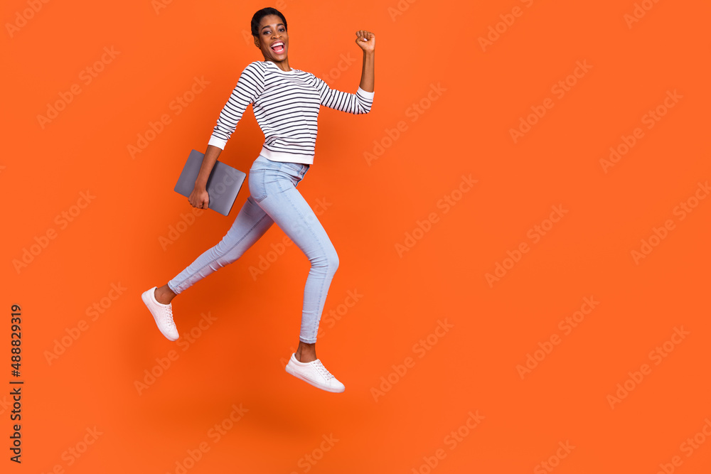 Photo of funny hurrying butch lady dressed sweater jumping holding gadget empty space isolated orange color background