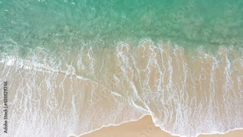 aerial top view sea waves seamless loop on the white sand beach. .Wave after wave swept towards the shore. .green sea, white bubble waves,and clear sand landscape. Paradise beach.