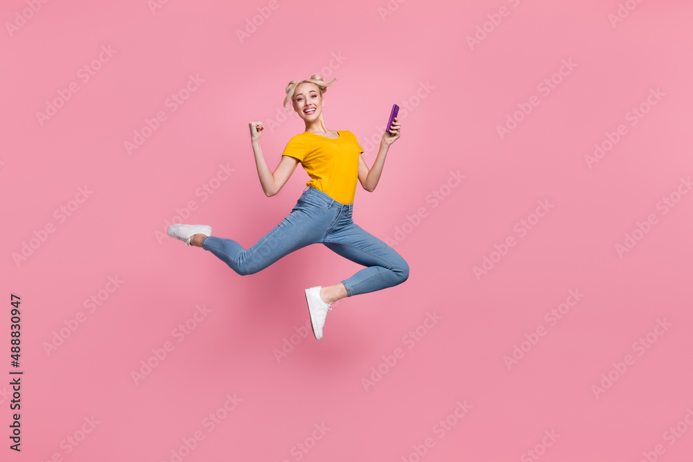 Full size photo of pretty blonde hair casual wear female jumping raise fists in triumph isolated on pink color background