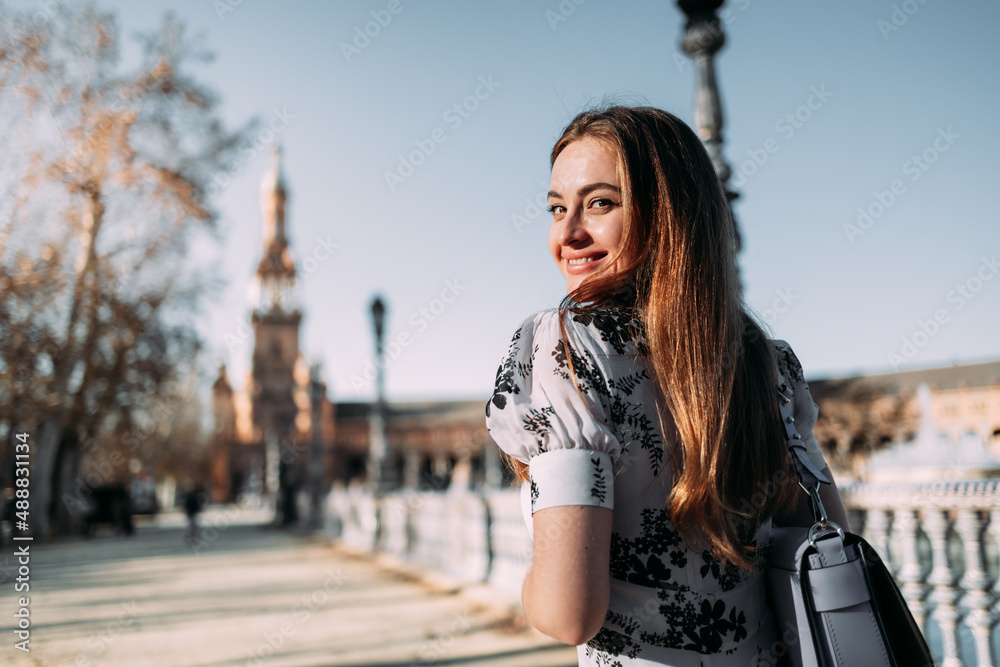 Beautiful smiling young woman turning to camera while sightseeing in Seville, Spain