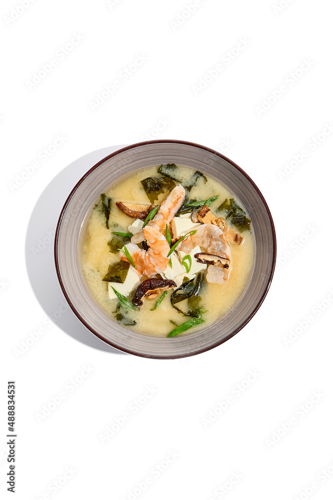 Japanese food - miso soup with tofu, wakame, prawn and shiitake mushroom. Miso soup with shrimp in ceramic bowl on isolated white background. Japanese food - miso soup with tofu, wakame, prawn and shiitake mushroom. Miso soup with shrimp in ceramic bowl on isolated white background.