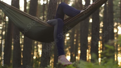 A happy girl is resting in a summer forest on a green hammock