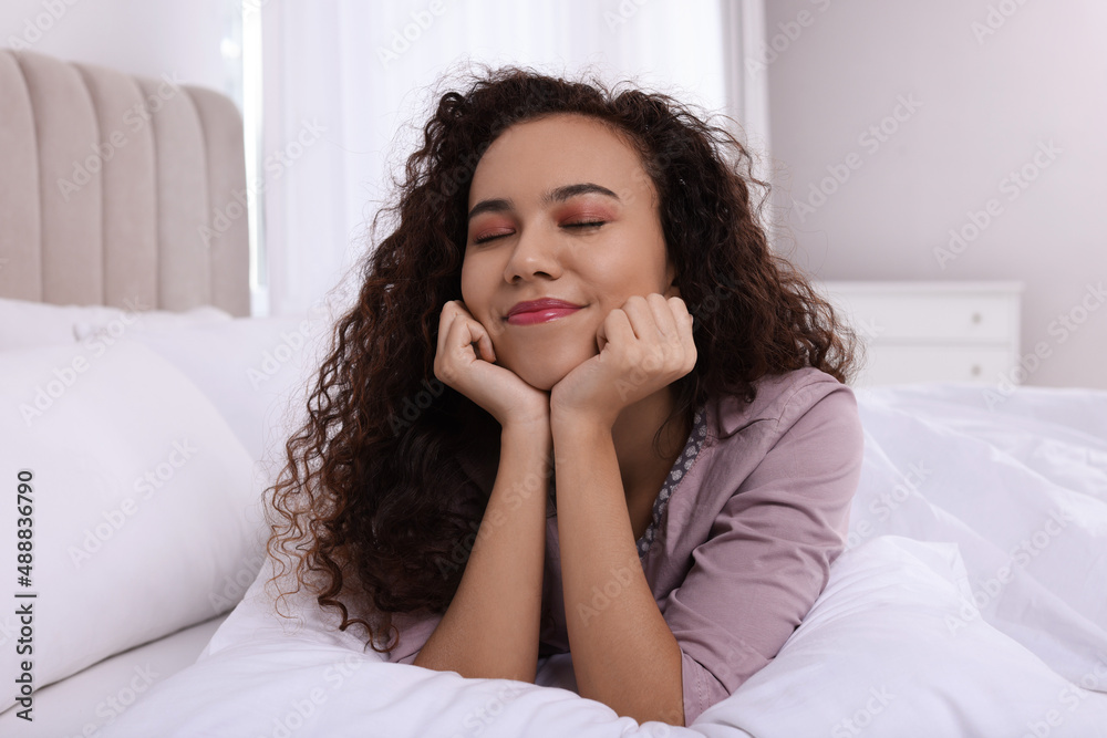 Happy African American woman lying on bed at home Happy African American woman lying on bed at home