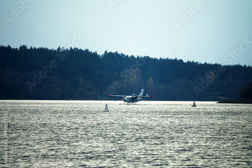 The Twin-engine seaplane a seaplane rises from water, from the forest lake, northern land. Utility seaplane photo