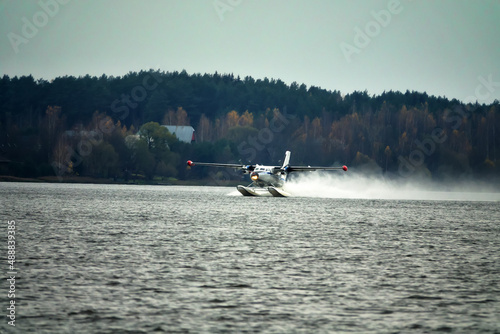 The Twin-engine seaplane a seaplane rises from water, from the forest lake, northern land. Utility seaplane photo