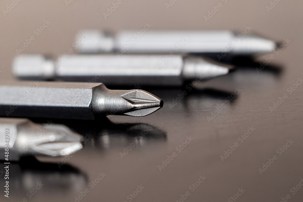 Bits for tightening screws on a dark brown background. Macro of screwdriver bits