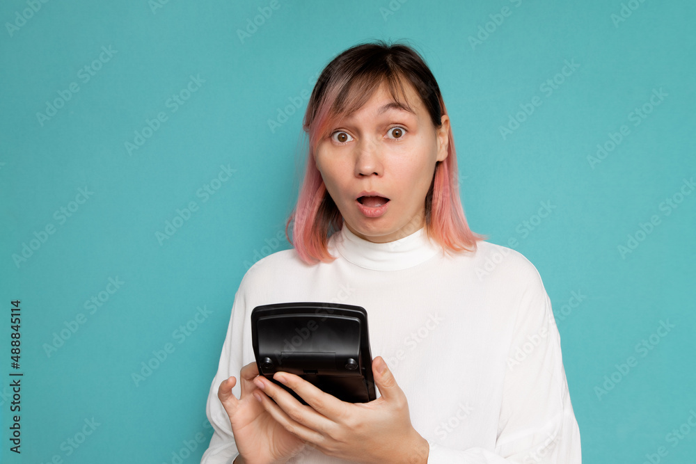 Portrait of a serious female accountant holding a calculator on a blue background. Portrait of a serious female accountant holding a calculator on a blue background.
