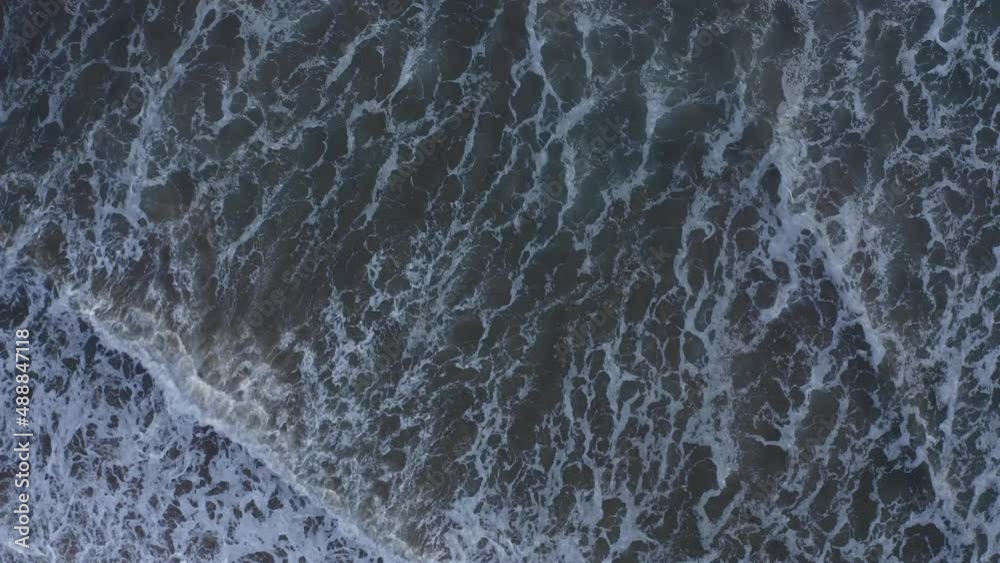 sea surf. Aerial top down view. Aerial ocean wave. Aerial top view sea waves foaming and splashing from above rolling and breaking on empty ocean beach. sea surf. Aerial top down view. Aerial ocean wave. Aerial top view sea waves foaming and splashing from above rolling and breaking on empty ocean beach.