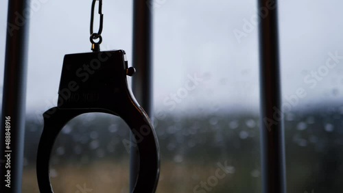 Handcuffs silhouette swing on prison bars