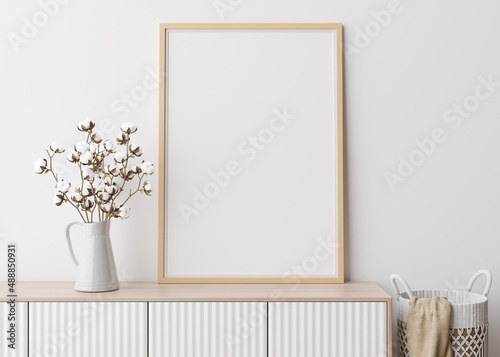 Empty vertical picture frame on white wall in modern living room. Mock up interior in minimalist, scandinavian style. Free space for picture. Console, rattan basket, cotton plant in vase. 3D rendering