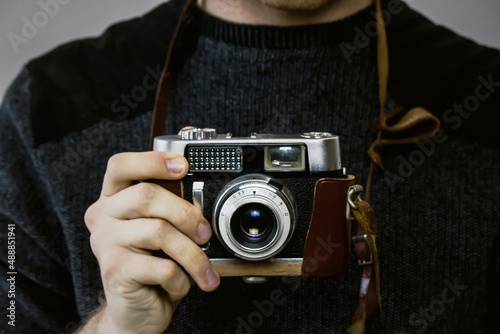 Man holds retro analog camera in his hand close-up