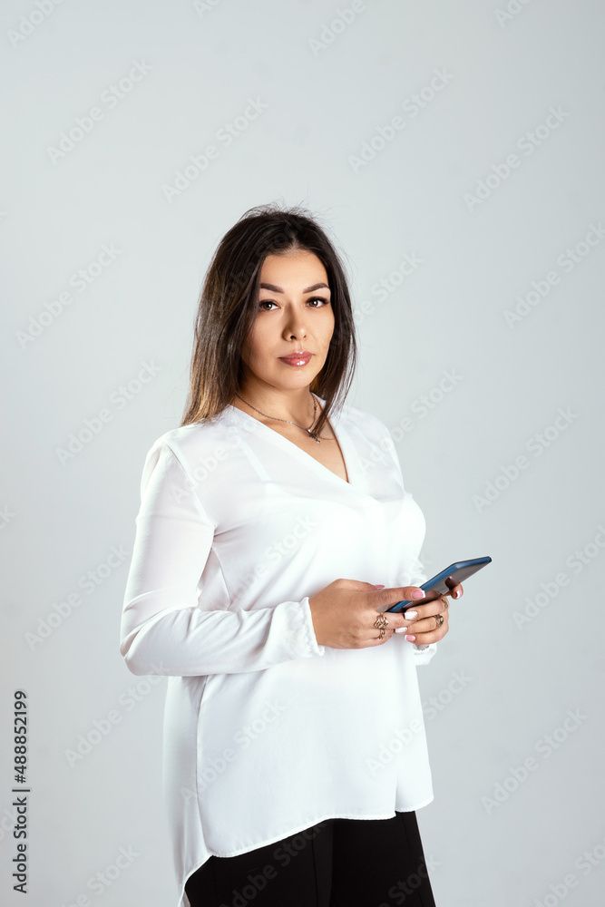 portrait of a young brunette woman speaks on the phone, office wear white blouse, isolated white background. business concept portrait of a young brunette woman speaks on the phone, office wear white blouse, isolated white background. business concept