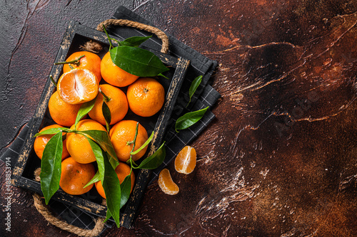 Fresh mandarin oranges or tangerines fruits with leaves. Dark background. Top view. Copy space