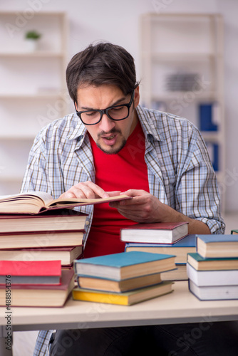 Young male student and too many books in the classroom