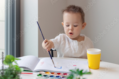 Portrait of a cute little boy drawing a picture. Charming child draws at the table, selective focus photo