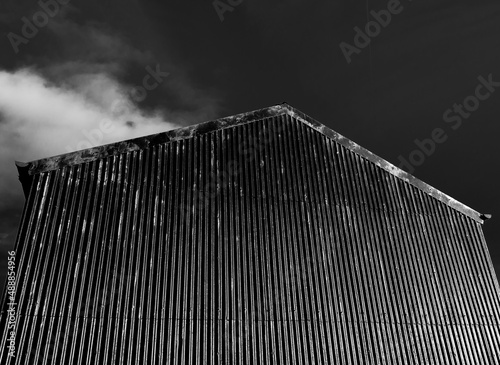 A black, corrugated metal barn against a black sky. In black and white. North Pennines, County Durham, England