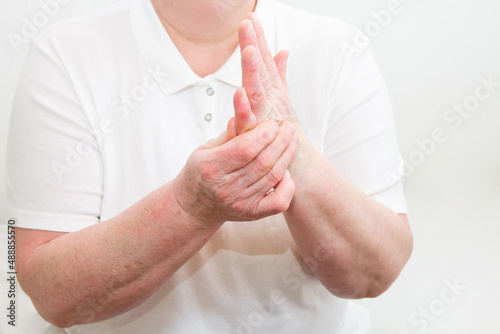 An elderly woman suffering from pain in her fingers close-up. An elderly lady touches her hand, joint pain, joint problems. An elderly woman is holding her sore hand.