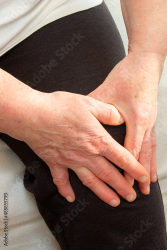 An elderly woman suffering from knee pain in close-up. An elderly lady touches her knee, joint pain, knee problems. An elderly woman is holding on to a sore knee.