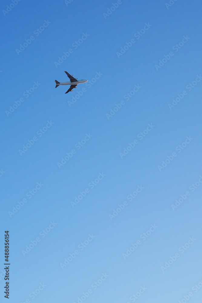 The big four-engine transport airplane is flying far away in the blue sky. Vertical illustration about international air freight The big four-engine transport airplane is flying far away in the blue sky. Vertical illustration about international air freight
