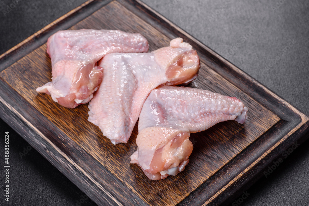 Chicken wings lie on a wooden board on a black background Chicken wings lie on a wooden board on a black background