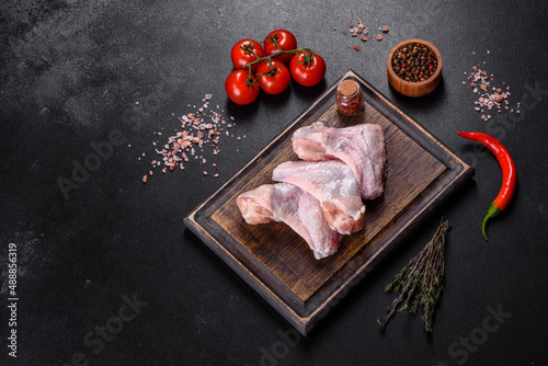 Chicken wings lie on a wooden board on a black background