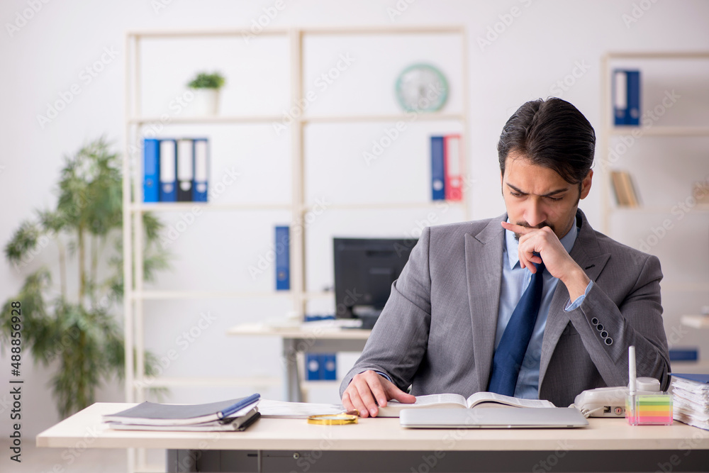 Young male employee reading book in the office Young male employee reading book in the office