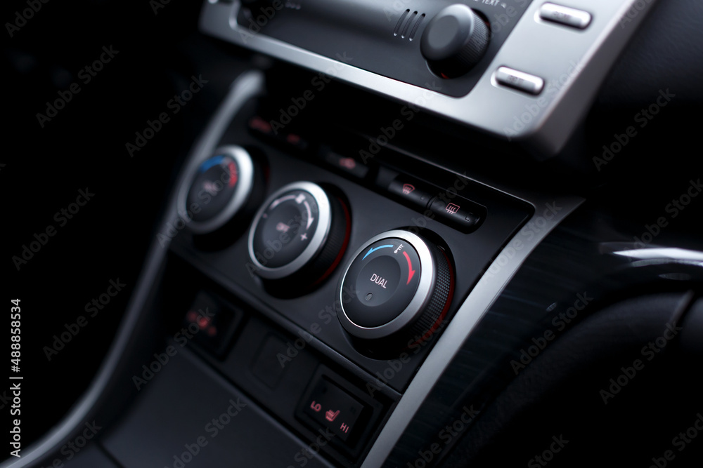 Car climate control panel for driver and passenger with shallow depth of field close up.