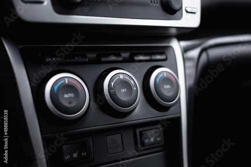 Car climate control panel for driver and passenger with shallow depth of field close up.
