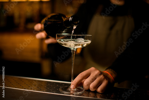 beautiful close-up of wine glass into which a drink is poured from a bottle