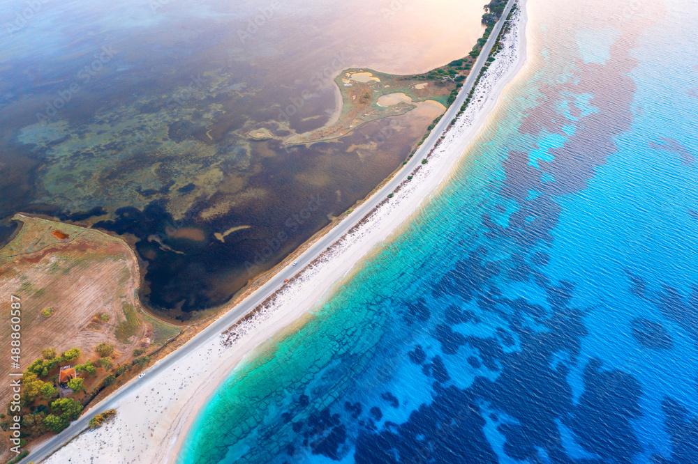 Aerial view of road near blue sea and river at sunset in summer. Lefkada, Greece. Top view of road between islands, white sandy beach, sea coast, clear water. Beautiful landscape. Top view from drone