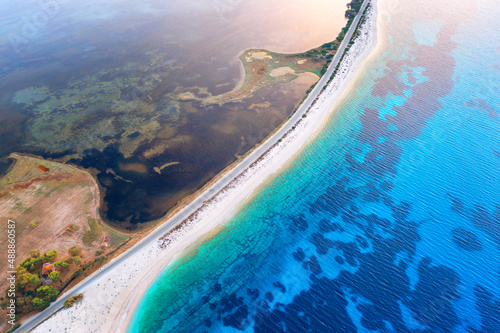 Aerial view of road near blue sea and river at sunset in summer. Lefkada, Greece. Top view of road between islands, white sandy beach, sea coast, clear water. Beautiful landscape. Top view from drone