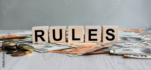 RULES inscription on the texture of wooden cubes. Wooden cubes on the background of banknotes. An inscription on a financial, business or economic theme.